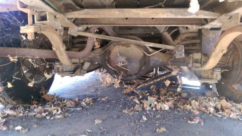 1968 Chevrolet C/K Pickup - The rear suspension and axle assembly of a classic pickup truck are visible, with extensive cobwebs and debris.