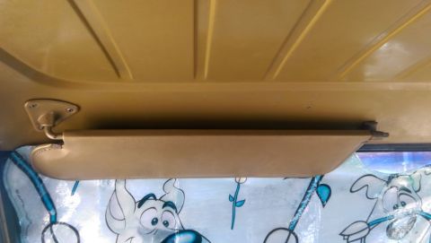 1968 Chevrolet C/K Pickup - The interior of a vehicle shows a sun visor and a yellow ceiling, with cartoon characters on the window.