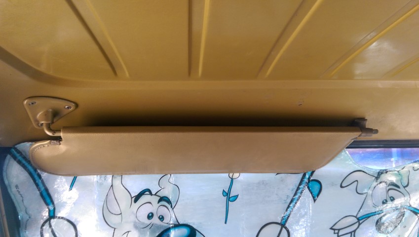 Interior shot of a vehicle's sun visor and ceiling. Cartoon characters are visible on the window