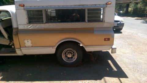 1968 Chevrolet C/K Pickup - A pickup truck with a camper shell is parked on a sunny day, with another vehicle visible in the background.