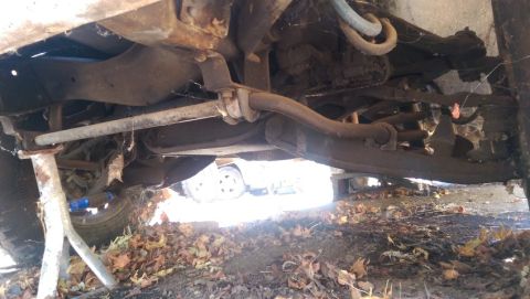 1968 Chevrolet C/K Pickup - Close-up of vehicle suspension parts and a tire, with fallen leaves on the ground.
