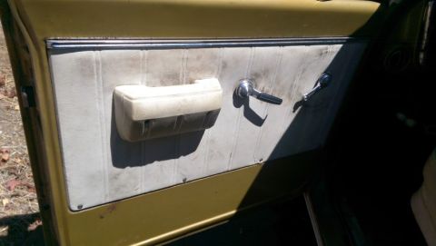 1968 Chevrolet C/K Pickup - A close-up view of a vintage truck's interior door panel, showing wear and tear.