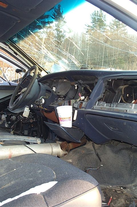 1991 Ford LTD Crown Victoria - The interior of a car shows significant damage, including a shattered windshield and missing dashboard components.