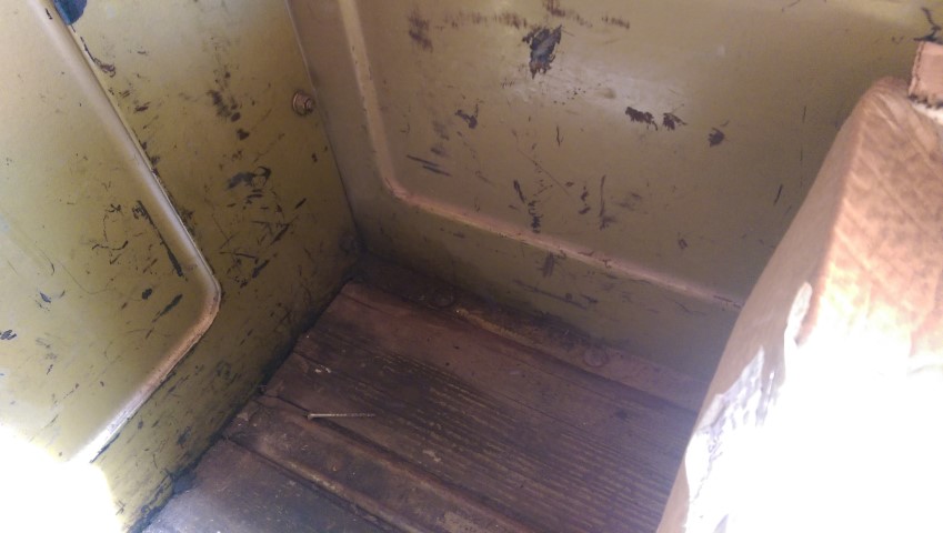 Interior corner of a truck bed showing yellow painted metal and a wooden floor