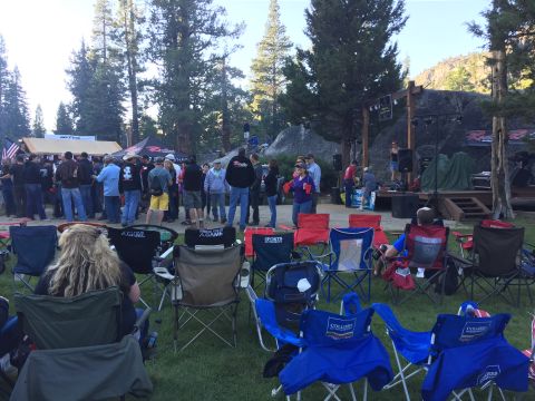 1946 Jeep CJ5 - An outdoor event with a stage set up for a performance, a crowd gathered, and camping chairs arranged in the foreground.
