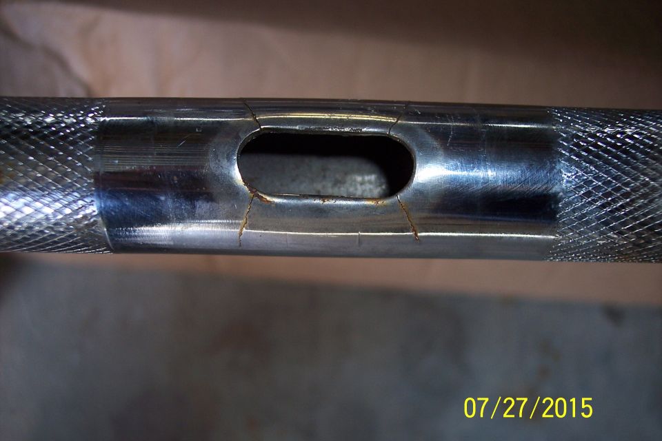 Chrome handlebar with a crack near the mounting hole. Knurled grips visible on ends