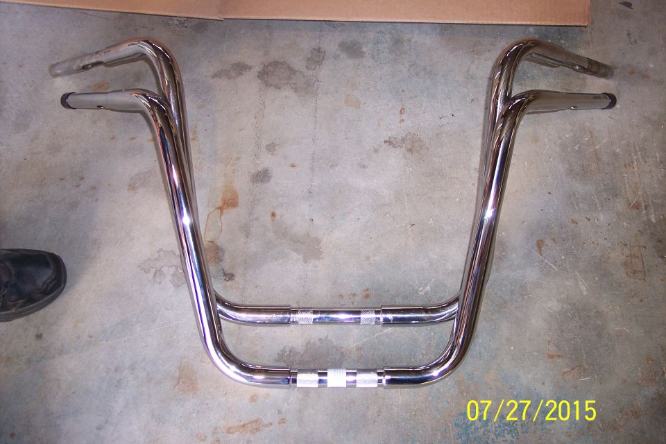 Chrome motorcycle handlebars with a double-crossbar design, resting on a concrete floor
