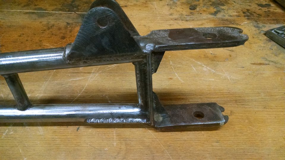 Close-up of a metal suspension component with welds and mounting holes