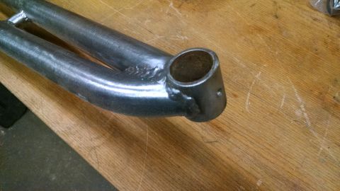 1992 Ford Bronco - Close-up of a metal suspension component, likely an extended radius arm, on a wooden workbench.