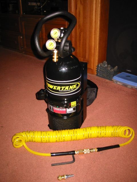 1985 Ford Bronco - A black Power Tank portable air compressor with a yellow coiled hose and two gauges is shown on a carpeted floor.