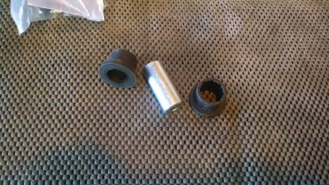 1992 Ford Bronco - Suspension bushings and a metal sleeve are laid out on a textured surface.