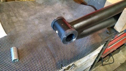 1992 Ford Bronco - A close-up view of a vehicle suspension part, possibly an extended radius arm, on a workbench.