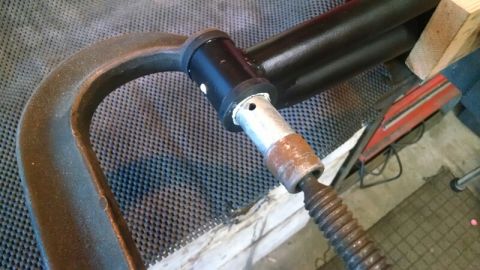 1992 Ford Bronco - A C-clamp is used to hold a metal component with a threaded rod attached.