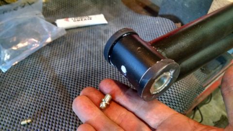 1992 Ford Bronco - Grease fitting and suspension part shown, with a tube of grease and a plastic bag in the background.