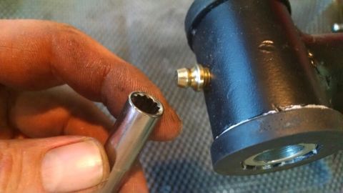 1992 Ford Bronco - A close-up of a socket wrench and a part with a grease fitting.
