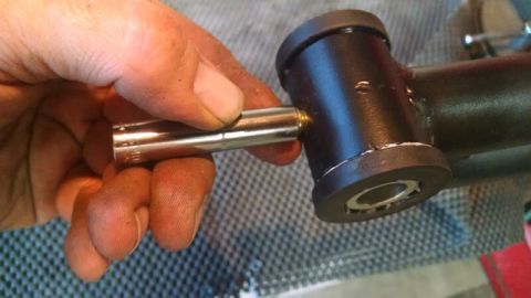 1992 Ford Bronco - Close-up of a hand using a socket wrench on a black suspension component, likely for a vehicle.