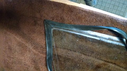 1992 Ford Bronco - A rubber seal for a vehicle window is laid out on a brown towel, ready for installation.