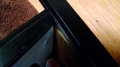 1992 Ford Bronco - A close-up view shows a black frame with a brown textured material and a wooden background.