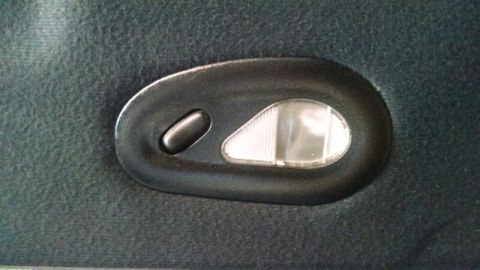1992 Ford Bronco - Interior dome light assembly with a push button and ribbed lens on dark fabric.