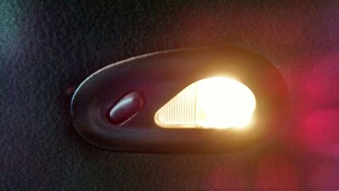1992 Ford Bronco - Close-up of a vehicle's interior dome light, showing the illuminated bulb and surrounding dark trim.