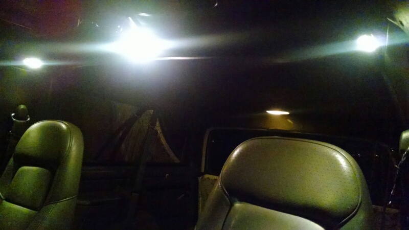 Interior shot of a vehicle with dome lights on, showing seats and ceiling