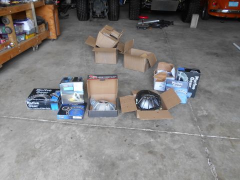 1992 Ford Bronco - Various automotive parts, including differential components, are arranged on a concrete surface in a garage setting.