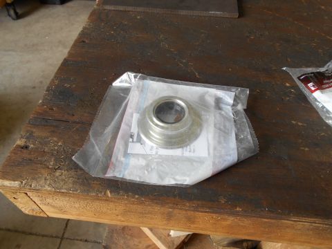 1992 Ford Bronco - A metal part, possibly a bearing race, is shown in its packaging on a wooden surface.
