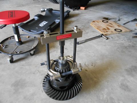1992 Ford Bronco - Tools are laid out on a garage floor next to a differential gear assembly being worked on with a puller tool.