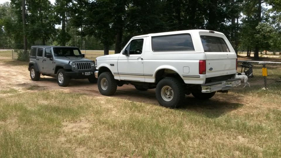 White 1996 Ford Bronco parked next to a grey Jeep Wrangler