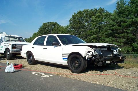 2001 Ford Crown Victoria - White 2001 Ford Crown Victoria with significant front-end damage, hooked up to a tow truck.