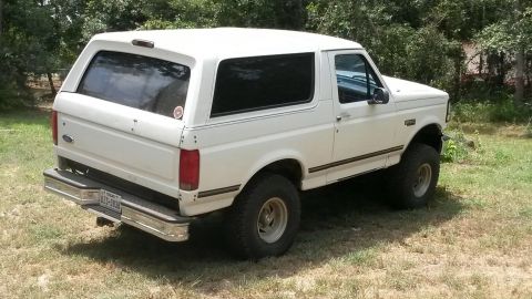 1996 Ford Bronco - A white Ford Bronco is parked on a grassy area with trees in the background.