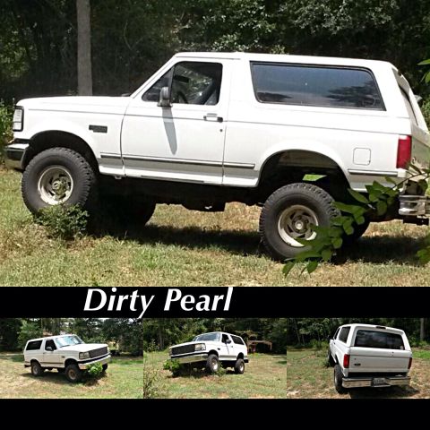 1996 Ford Bronco - White 1996 Ford Bronco parked off-road with trees in the background.
