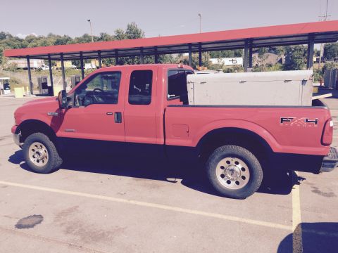 2006 Ford F-250 - A red Ford F-250 pickup truck is parked outside under a covered structure.