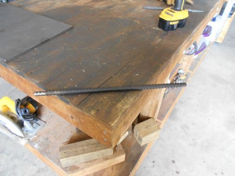 1992 Ford Bronco - A piece of rebar rests on a workbench, alongside a circular saw and a cordless drill.