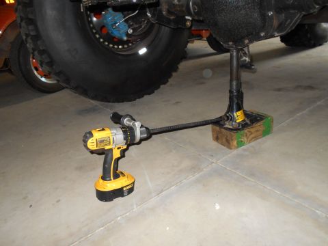 1992 Ford Bronco - A power drill is used to operate a jack lifting a vehicle's rear axle.