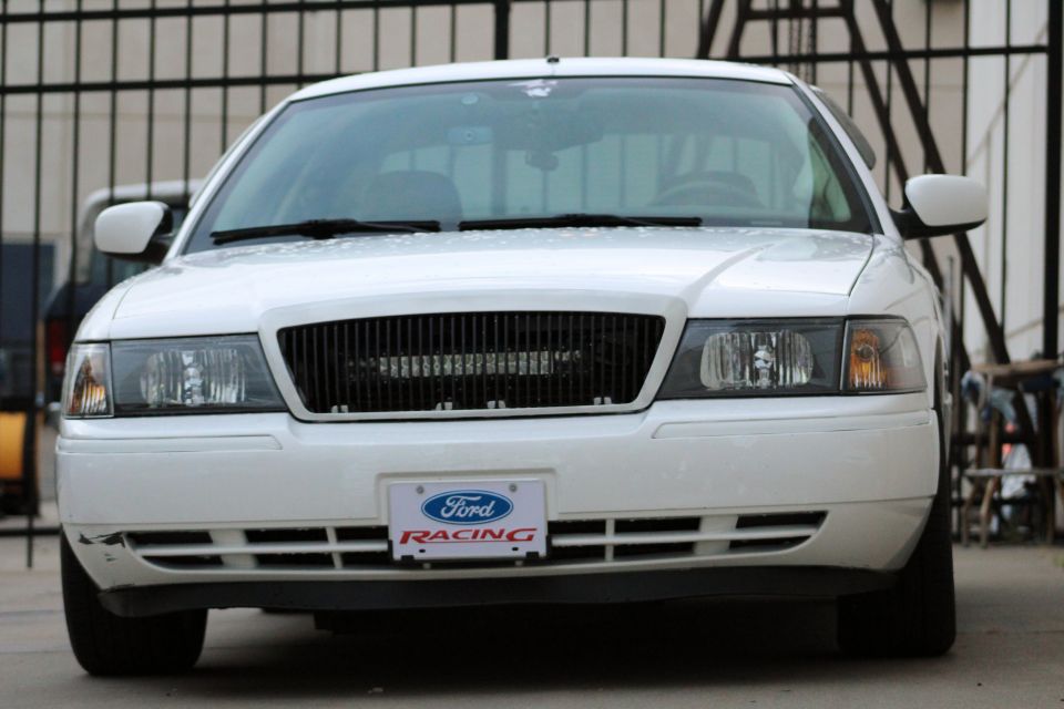 White sedan front view, black grille, Ford Racing license plate frame