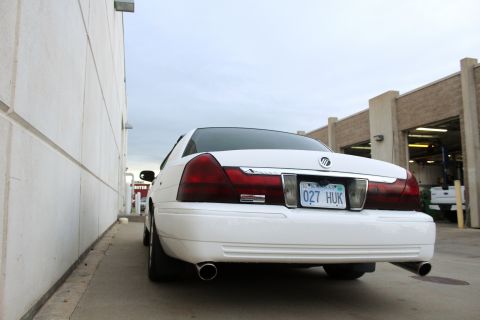 2000 Mercury Grand Marquis - The rear of a white Mercury Grand Marquis is shown parked next to a building with its dual exhaust pipes visible.