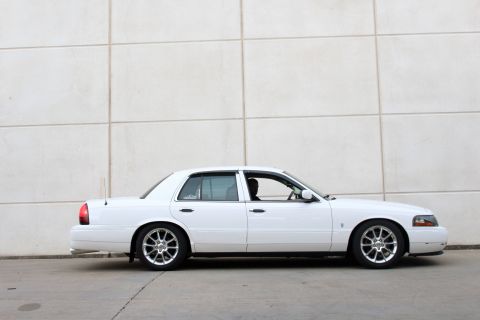 2000 Mercury Grand Marquis - Side profile of a white 2000 Mercury Grand Marquis sedan with aftermarket wheels.