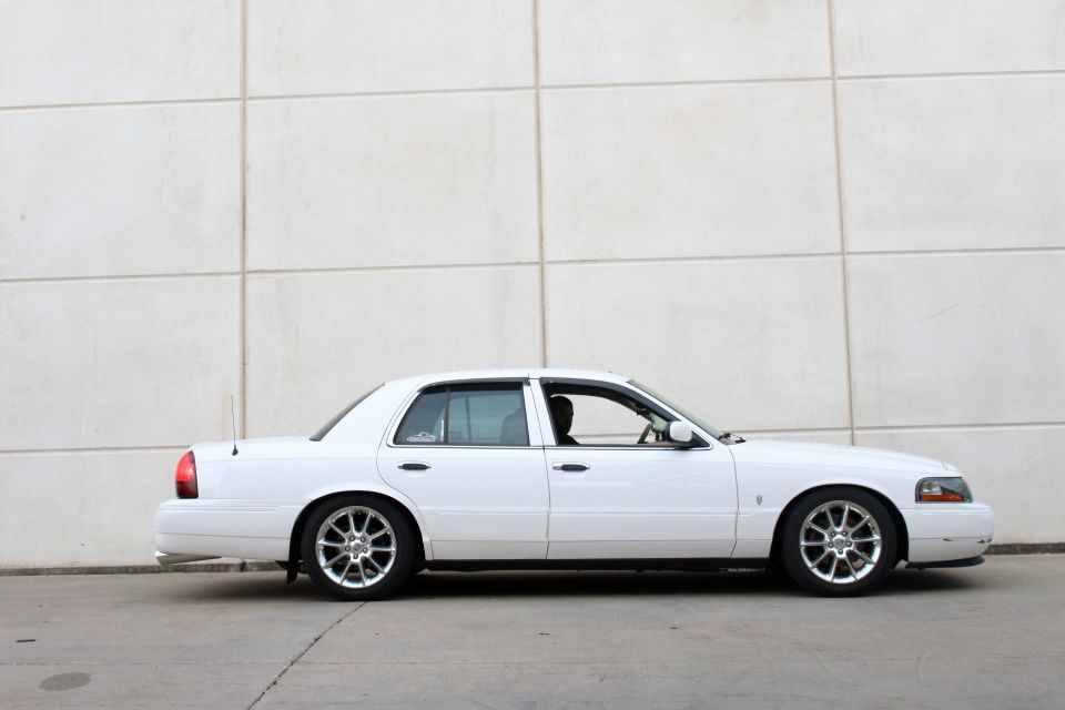 White 2000 Mercury Grand Marquis sedan, side view, parked against a tiled wall