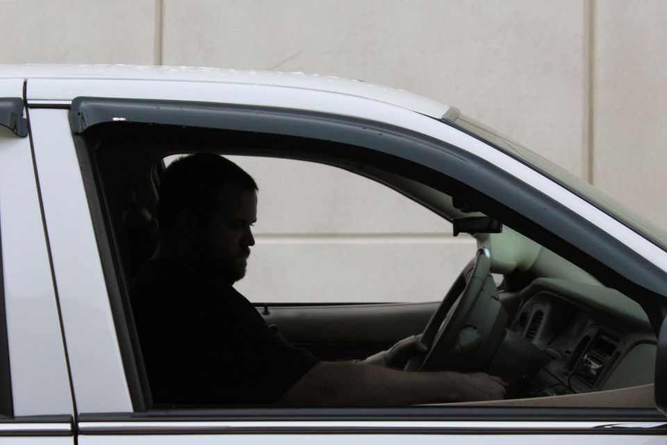 White sedan interior with driver, side view. Dashboard and steering wheel visible