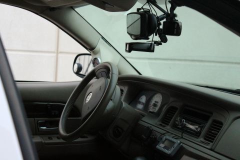2000 Mercury Grand Marquis - Dashboard and steering wheel of a 2000 Mercury Grand Marquis, aftermarket dashcam and radar detector.