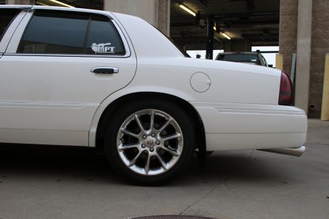 2000 Mercury Grand Marquis - Rear side view of a white sedan with aftermarket wheels and a decal on the rear passenger window.