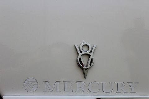 2000 Mercury Grand Marquis - Close-up of the Mercury lettering and V8 badge on a white vehicle.