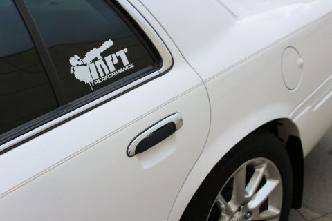 2000 Mercury Grand Marquis - A white sedan's side profile, a chrome door handle and a performance sticker on the rear window.