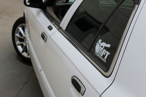 2000 Mercury Grand Marquis - Side view of a white sedan a performance sticker on the rear passenger window.
