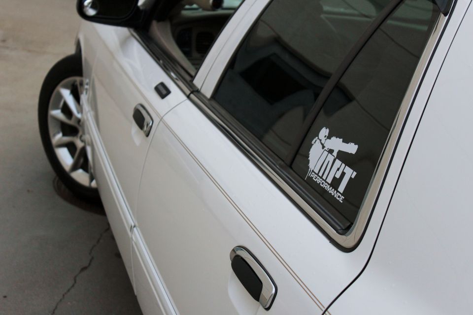 White sedan side view with performance sticker on rear window
