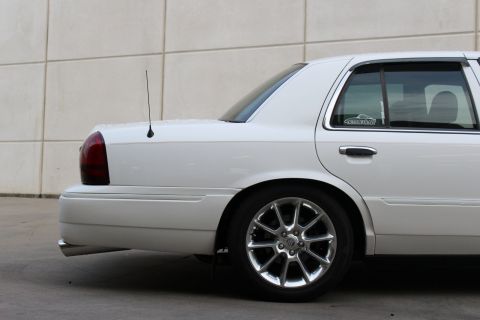 2000 Mercury Grand Marquis - A white sedan is shown from the rear quarter panel, highlighting its chrome wheels and tinted windows.