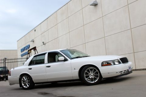 2000 Mercury Grand Marquis - A white sedan is parked in front of a building with a "BODY SHOP" sign, showing its front and side profile.