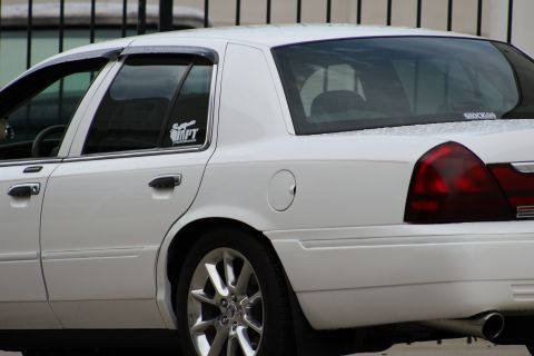 2000 Mercury Grand Marquis - Side profile of a white 2000 Mercury Grand Marquis sedan with tinted windows and chrome wheels.