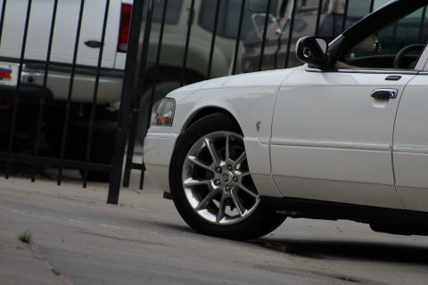 2000 Mercury Grand Marquis - A white sedan is partially visible from the front quarter panel, showing its wheel and door handle.